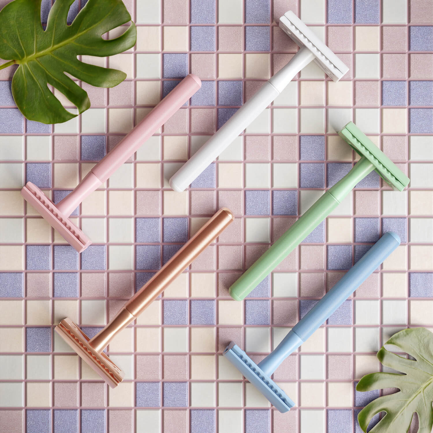 3D render of pastel coloured razors arranged on a tiled surface with leaves
